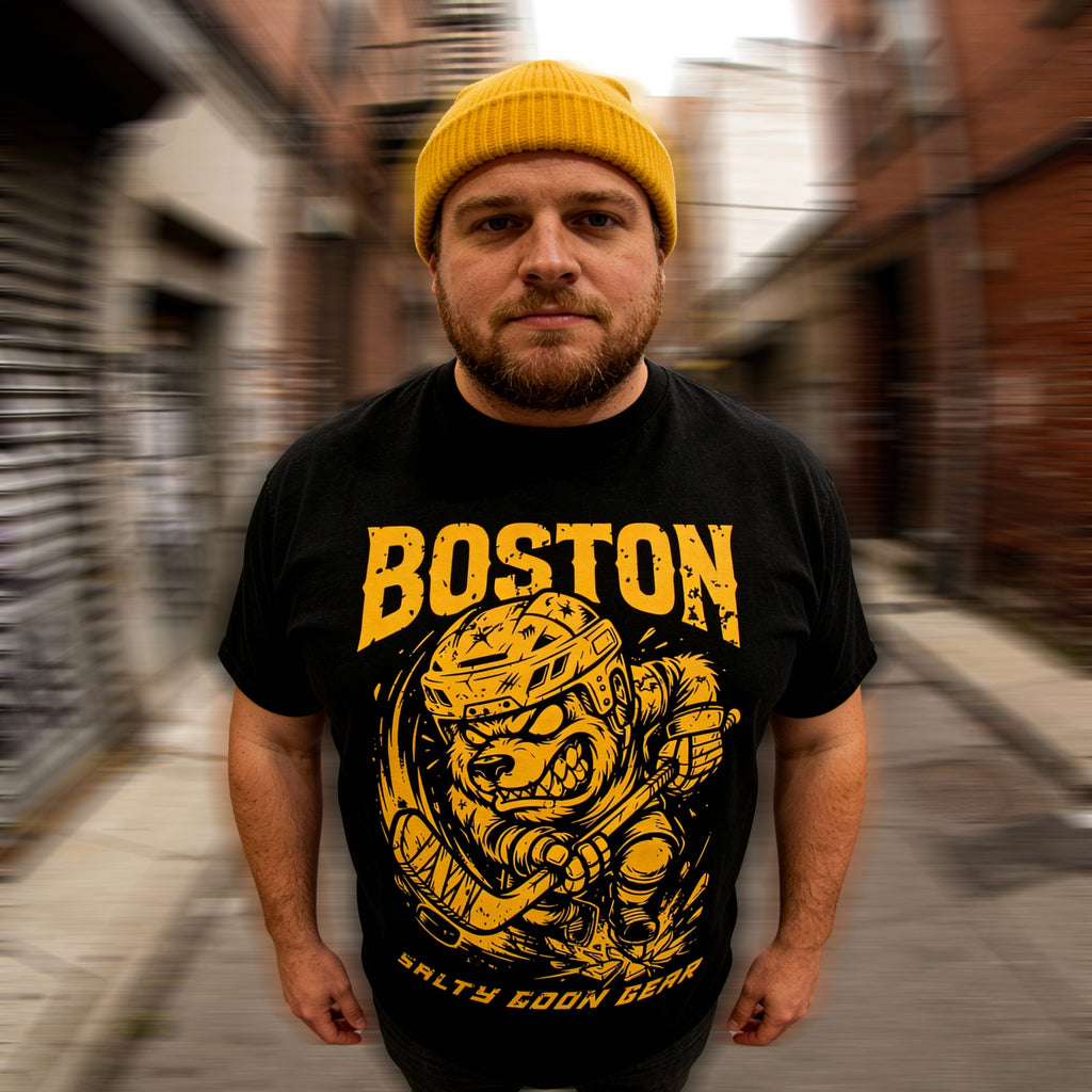 Man wearing a black t-shirt with BOTSON HOCKEY yellow graphics and text in an urban setting