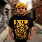 Man wearing a black t-shirt with BOTSON HOCKEY yellow graphics and text in an urban setting