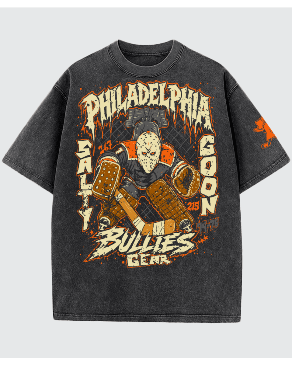 A dark gray mineral-wash graphic t-shirt featuring a hockey goalie design with the text 'PHILADELPHIA" salty goon gear in distressed orange and cream lettering, shown against a light gray background.