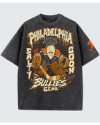 A dark gray mineral-wash graphic t-shirt featuring a hockey goalie design with the text 'PHILADELPHIA" salty goon gear in distressed orange and cream lettering, shown against a light gray background.