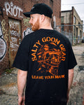 Man wearing a black t-shirt with 'Salty Goon Gear' logo and text, standing in an urban setting.
