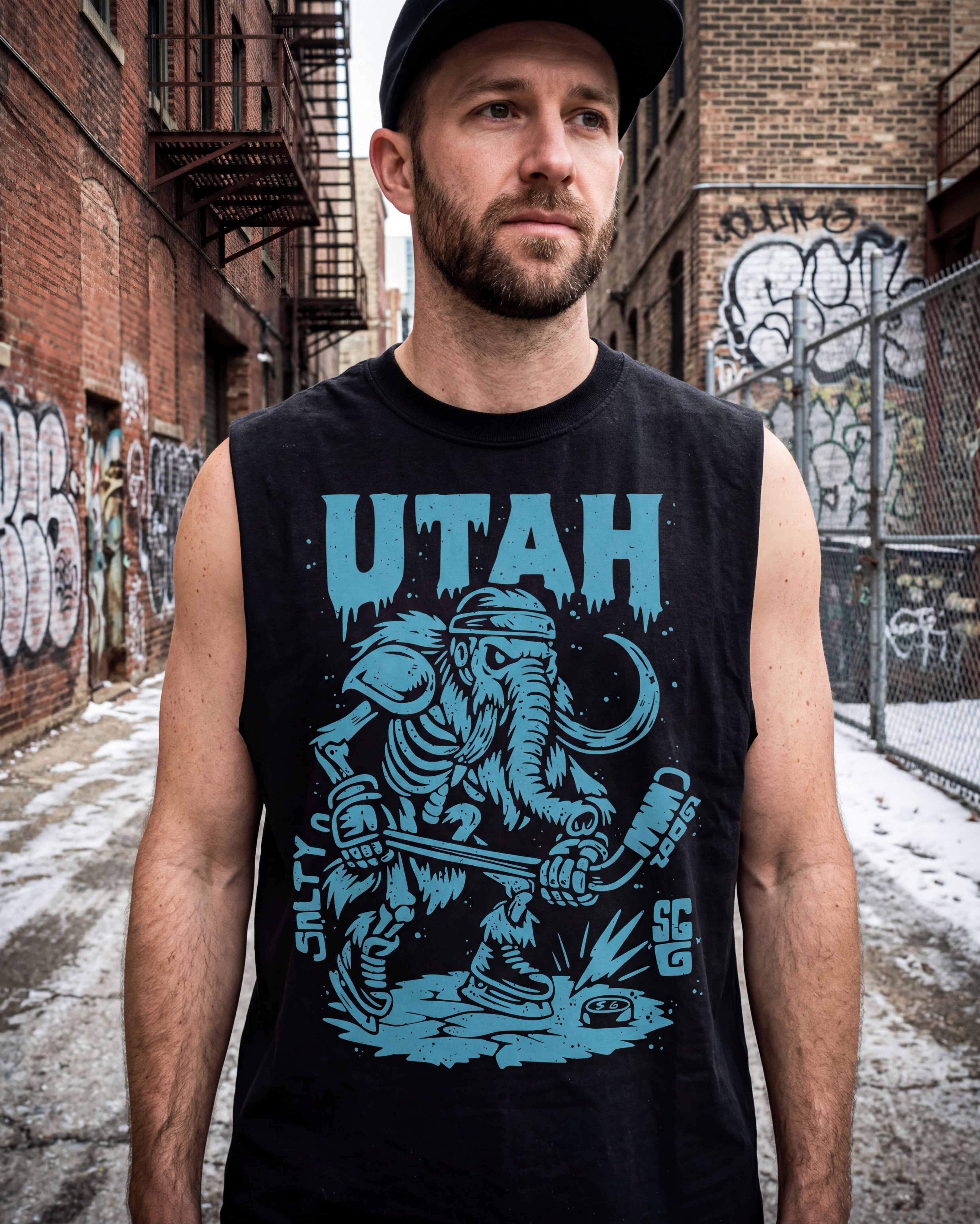 Man wearing a black sleeveless shirt with 'Utah' and a graphic design in an urban setting.