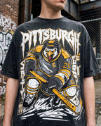 A person wearing a black Pittsburgh Hockey graphic t-shirt with a distressed wash, featuring a hockey player design and the team name in stylized lettering.