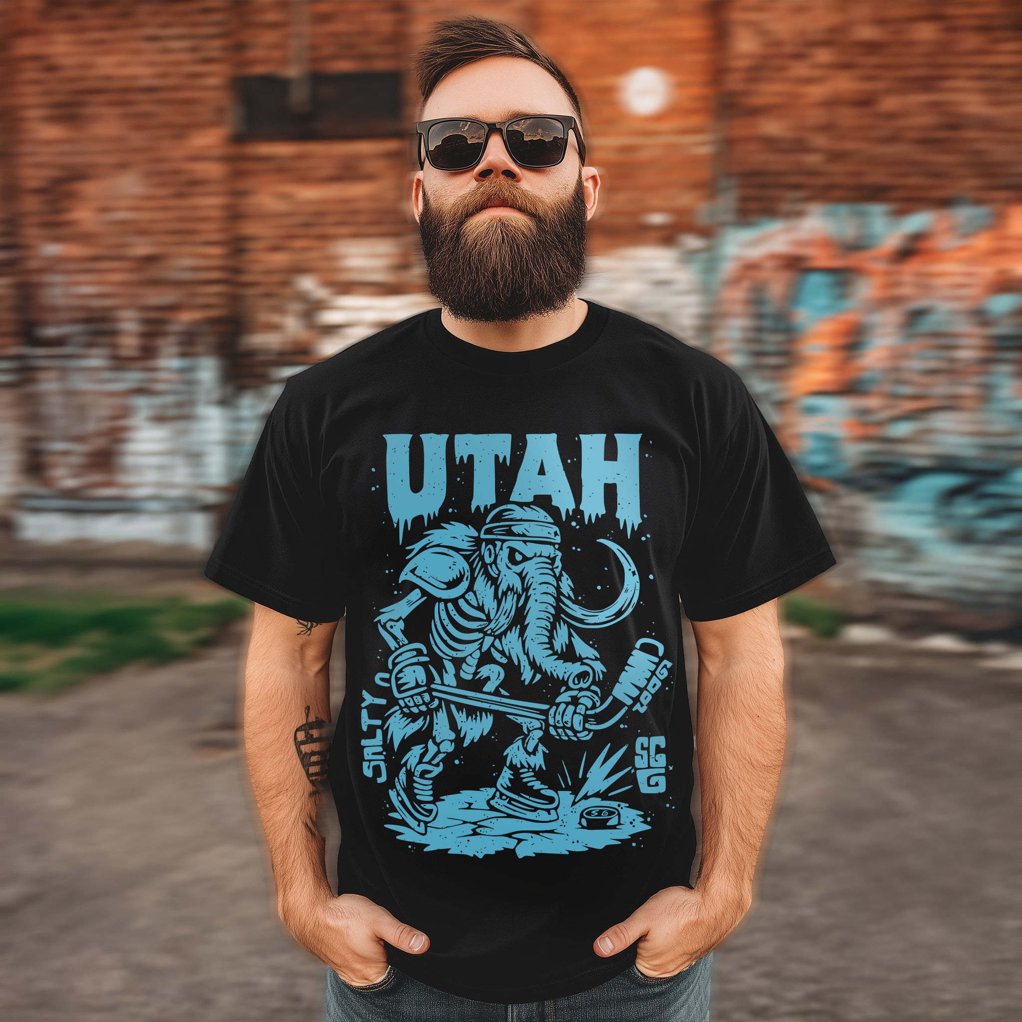 Man wearing a black t-shirt with 'Utah' design in front of a graffiti-covered wall.
